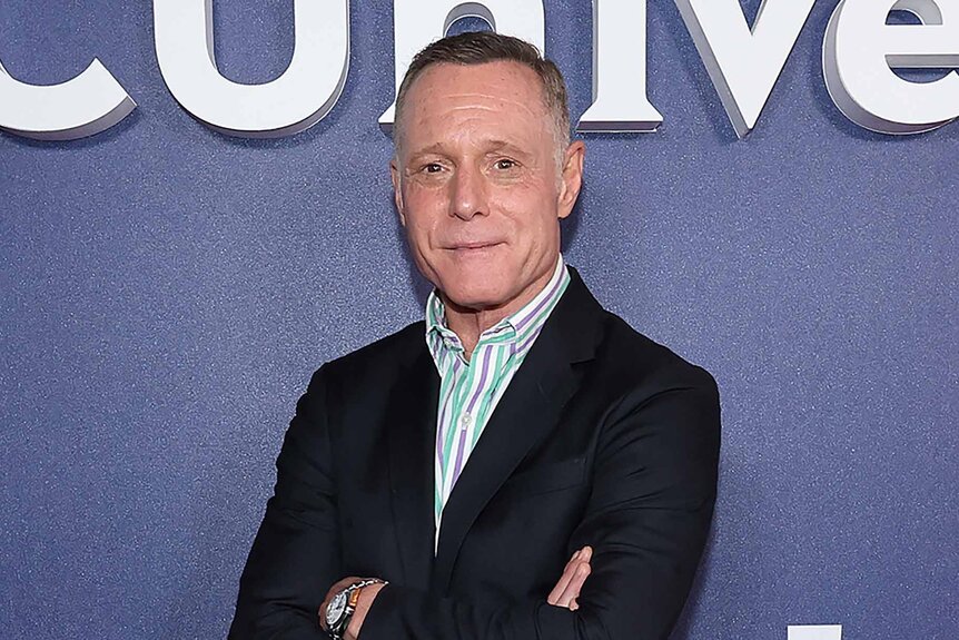 Jason Beghe smiles in a suit.