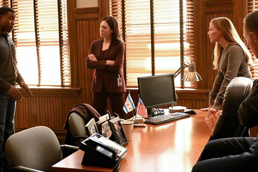 Jason Bowen, Asa Chapman, Hailey Upton, and Hank Voight discuss around a large table in an office on Chicago P.D. Season 11 Episode 1.