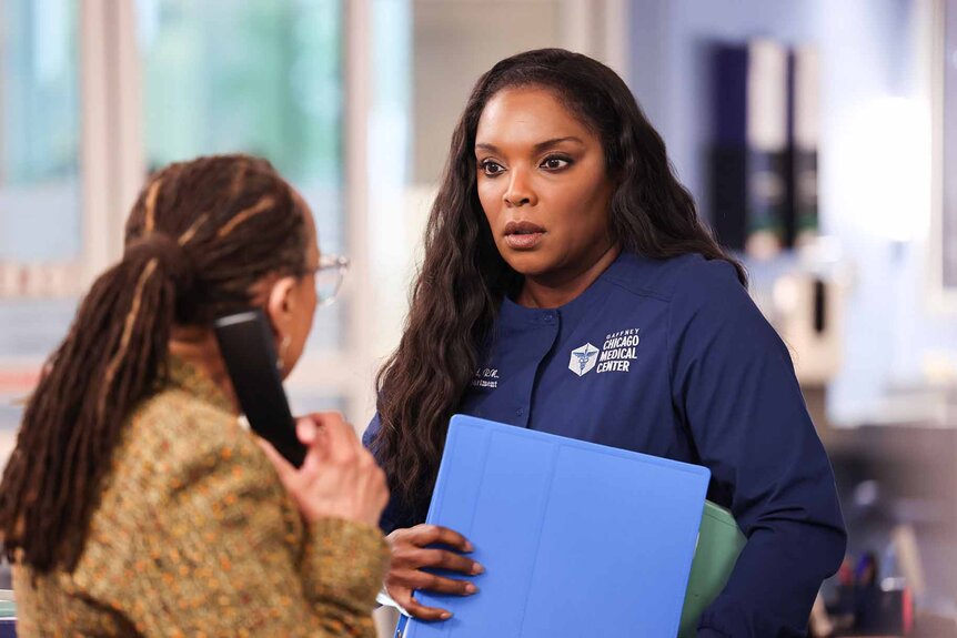 Sharon Goodwin listens to Maggie Lockwood speak while holding a phone in Chicago Med Episode 902.