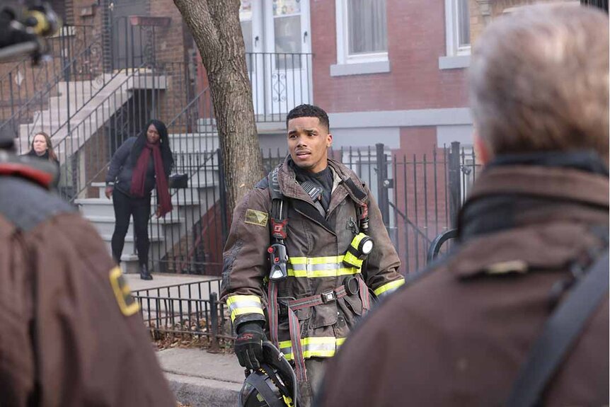 Derrick Gibson looks stressed in firefighting gear on the street in Chicago Fire Episode 1202.