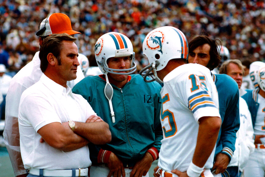 Don Shula, Coach of the Miami Dolphins speaks with Quarterback Bob Griese and Quarterback Earl Morrall during an NFL football game against the Baltimore Colts