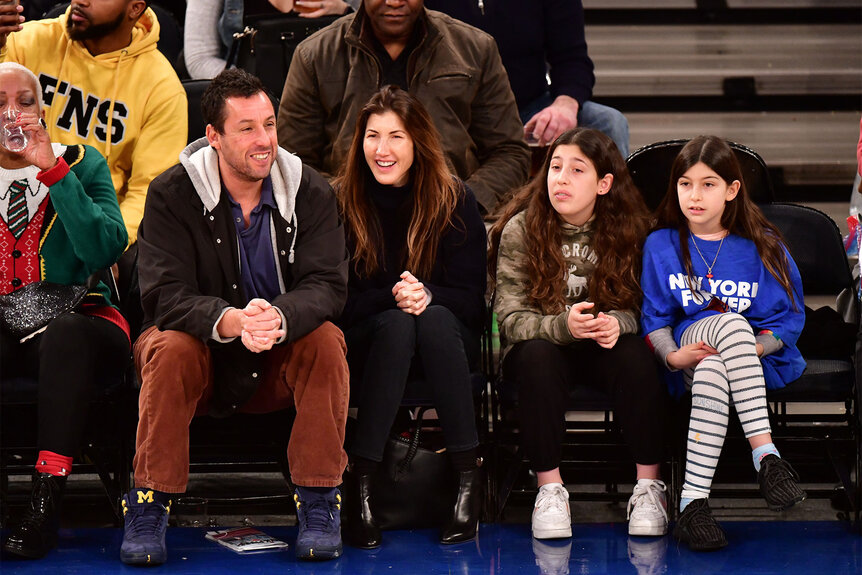 Adam Sandler, Jackie Sandler, Sadie Sandler and Sunny Sandler sit courtside at the Milwaukee Bucks v New York Knicks game