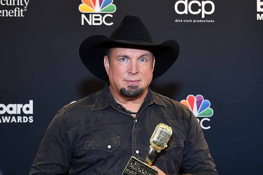 Garth Brooks wears a black cowboy hat and poses with an Icon Award.