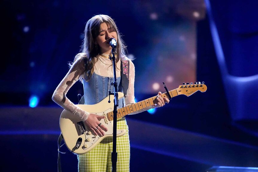 Anya True sings while playing guitar in Season 25 Episode 4 of The Voice.