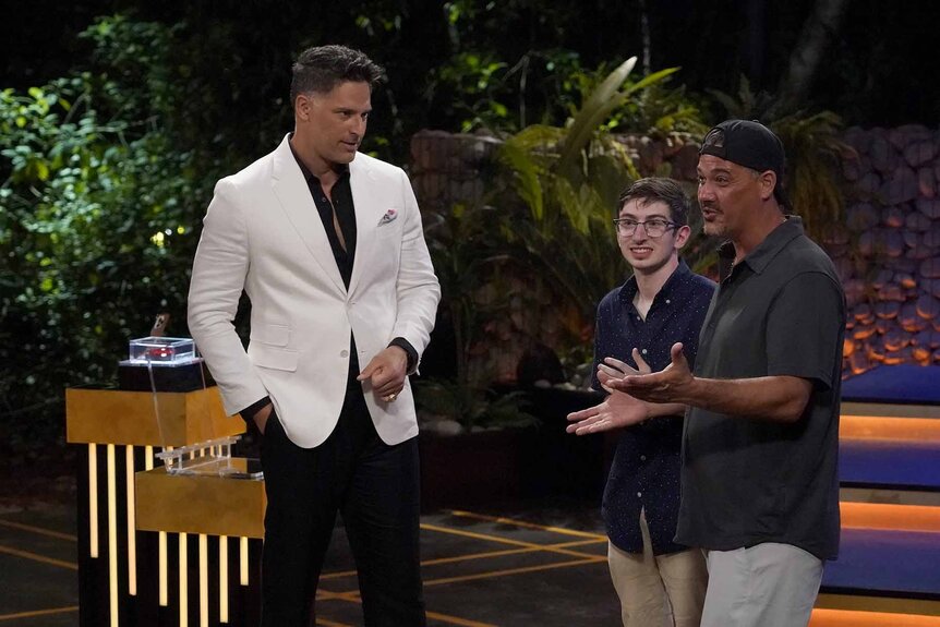 Joe Manganiello wears a white suit jacket next to Aron Barbell and Rob Mariano in Deal or No Deal Island Episode 102.