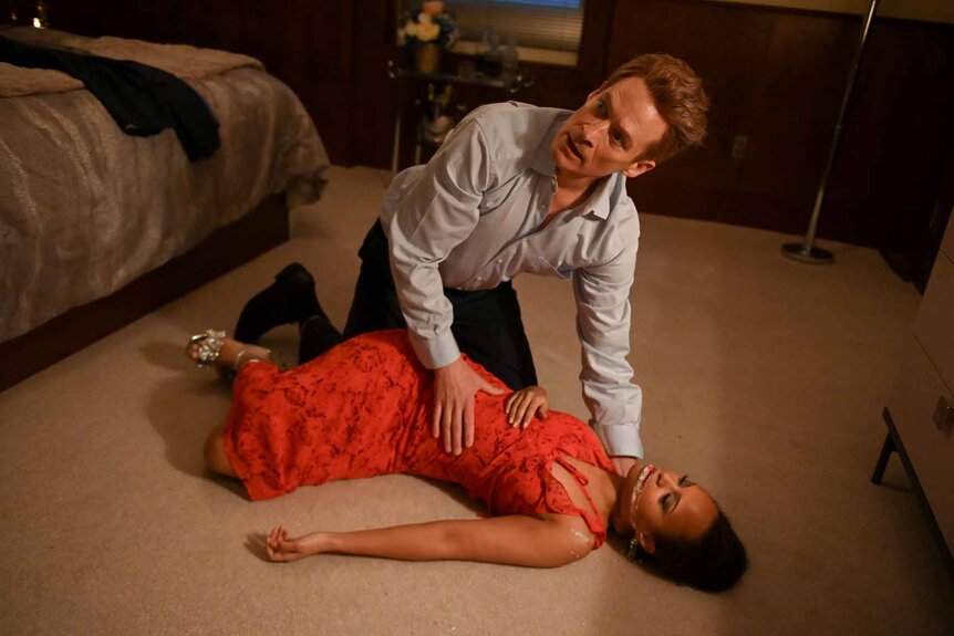 Senator Kevin Sanford kneels over Natalie's unconscious body in The Irrational Episode 111.