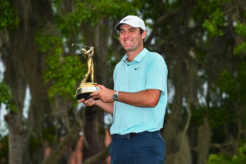 Scottie Scheffler smiles holding the tournament trophy at the players championship