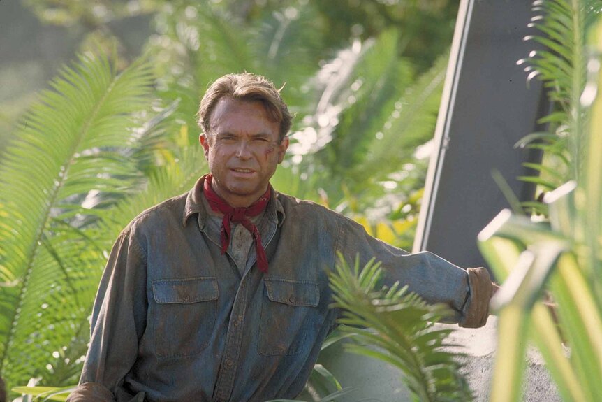 Dr. Alan Grant (Sam Neill) stands next to an electric fence in Jurassic Park (1993).