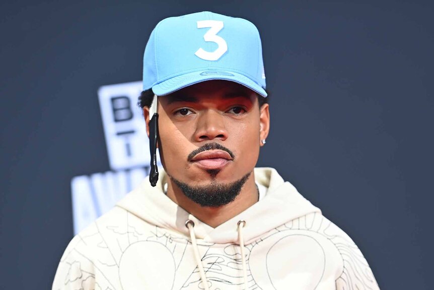 Chance the Rapper poses in a hoodie and his signature "3" hat.