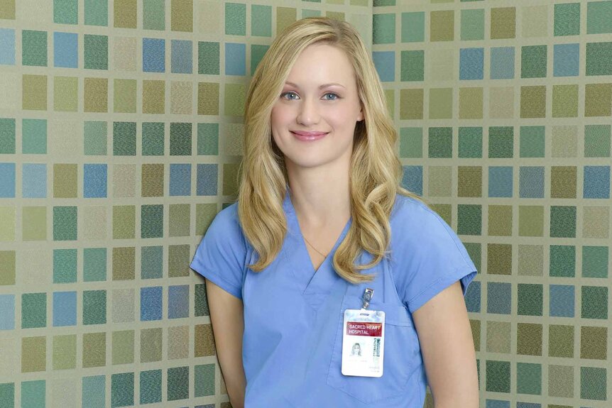 Lucy Bennett (Kerry Bishe) smiles in front of a tiled background.