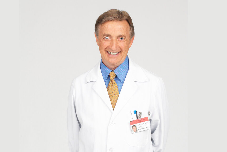 Dr. Bob Kelso smiles in his white coat in Scrubs Season 1.