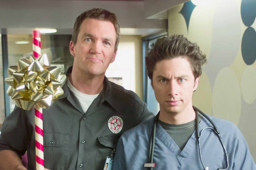The Janitor (Neil Flynn) holds a holiday stick next to Dr. John 'J.D.' Dorian in Scrubs Episode 203.