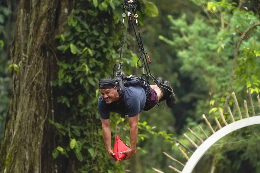 Rob Mariano ziplines holding a red pyramid on Deal or No Deal Island Episode 103