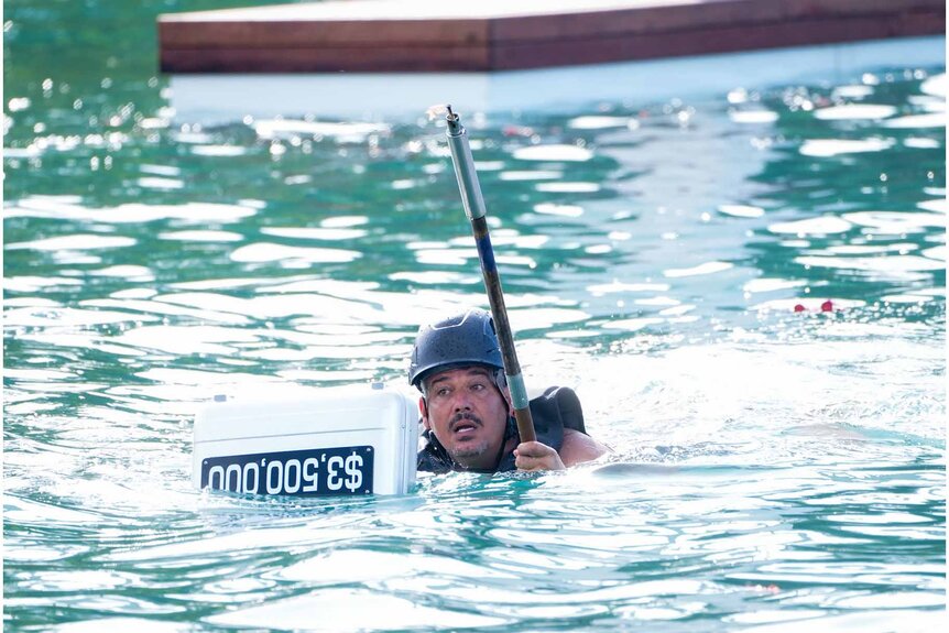 Rob Mariano swims with a briefcase in Deal or No Deal Island Episode 106.