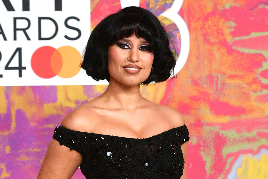 Raye poses on the red carpet of the BRIT awards in a black dress