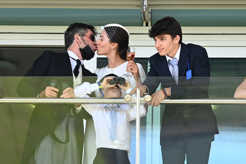 Simon Cowell and US socialite Lauren Silverman, along with their children Eric and Adam, gesture as they watch the action with other racegoers on the second day of the Epsom Derby Festival