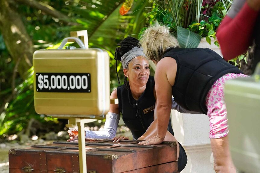 Stephanie Mitchell talks behind a golden $5 million briefcase in Deal or No Deal Island Episode 107.