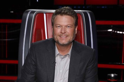 Blake Shelton smiles in a red chair on The Voice Episode 2217A.